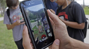 FILE - In this Tuesday, July 12, 2016, file photo, Pinsir, a Pokemon, is found by a group of Pokemon Go players at Bayfront Park in downtown Miami. The "Pokemon Go" craze has sent legions of players hiking around cities and battling with "pocket monsters" on their smartphones. (AP Photo/Alan Diaz, File)
