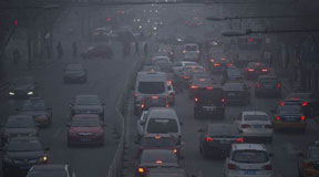 FILE - In this Dec. 25, 2015, file photo, pedestrians make their way across a busy intersection on a day with severe air pollution in Beijing. Average concentrations of air particulates in 189 Chinese cities fell by 10 percent in 2015, according to a new Greenpeace report, a sign that pollution overall is decreasing even as catastrophic levels of smog this winter in northern China effectively shut down schools and roads. (AP Photo/Mark Schiefelbein, File)