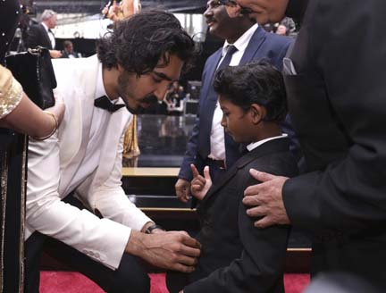 Dev Patel buttons the jacket of his co-star Sunny Pawar at the Oscars on Feb. 26, at the Dolby Theatre in Los Angeles.