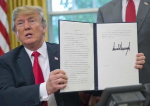 President Donald Trump holds up the executive order he signed to end family separations