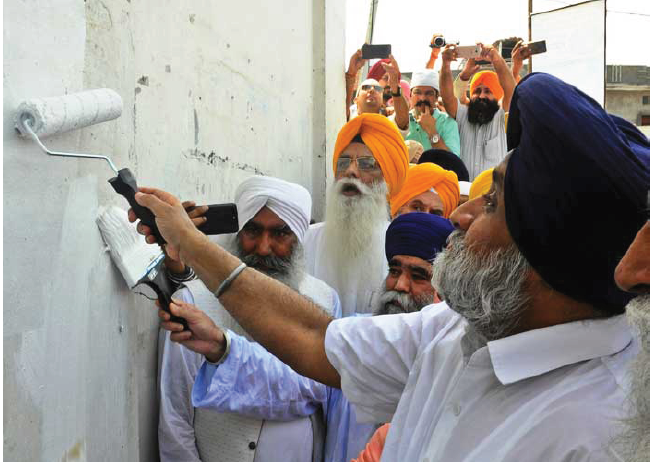 SAD president Sukhbir Singh Badal painting white a portion of a gurdwara wall for launching the project
