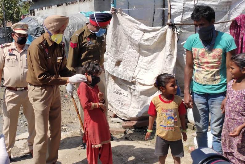 City SHO Inspector Onkar Singh Brar teaching a kid of slum dwellers how to wear a mask to save themselves from Coronavirus