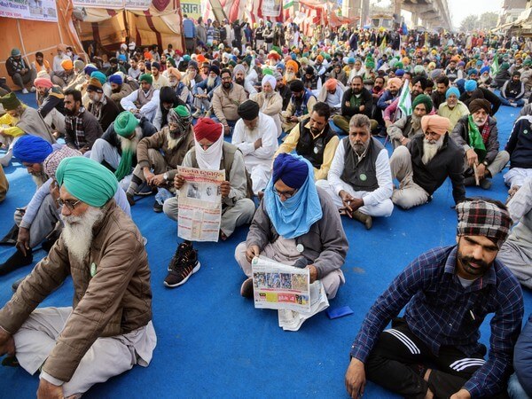 Farmers read newspapers during an ongoing protest