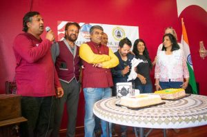 (L-r in front) Dhaval Shah sings with Dr. Japra, Satish Vale (for who the birthday cake was being cut), Prakash Thapa, Saroj, and Ritu Maheswari, and others at the back